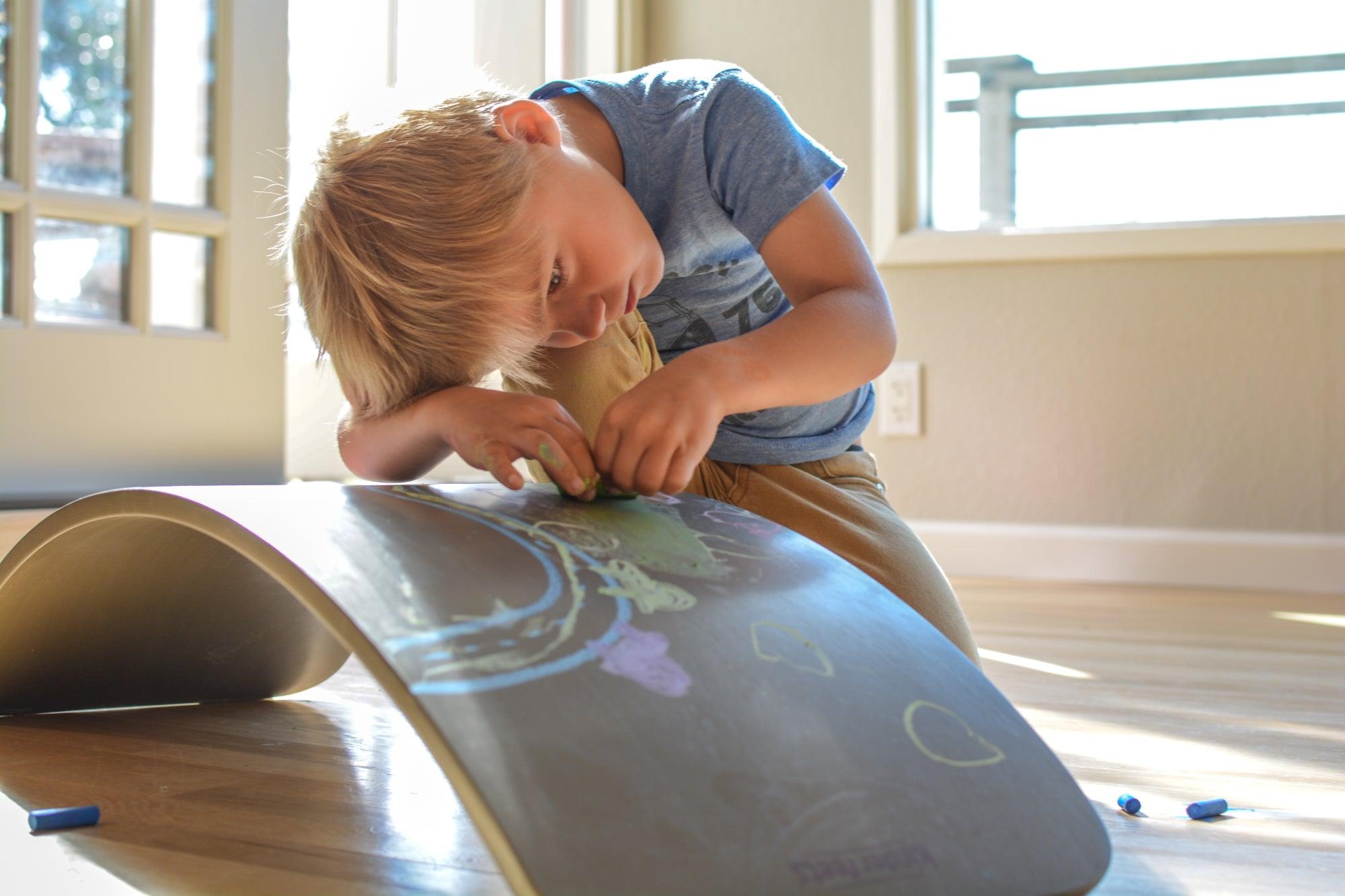 Kinderfeets Kinderboard balance board with chalkboard surface, featuring colorful handles and sturdy wooden construction.