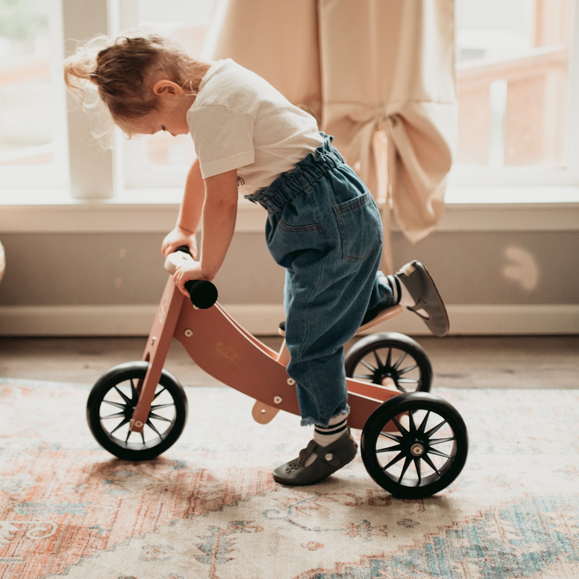 Kinderfeets Tiny Tot coral balance bike for toddlers, featuring a lightweight frame and easy-to-grip handlebars.