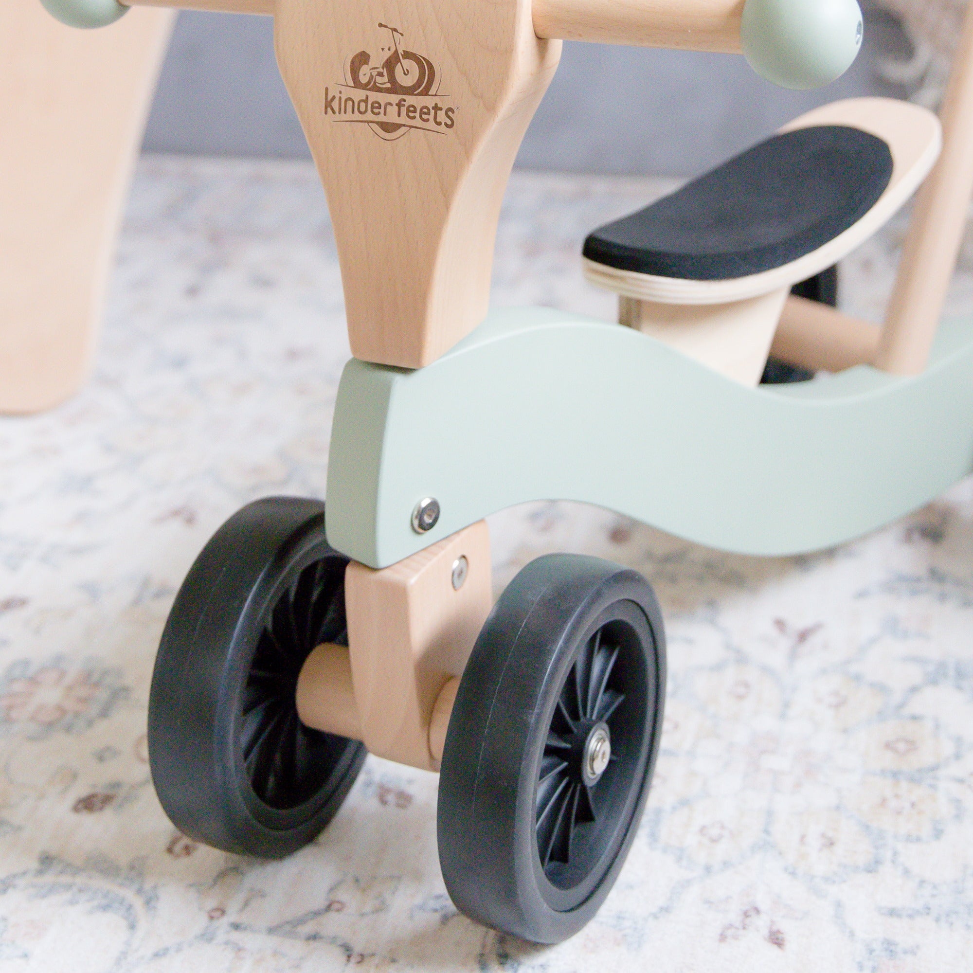 Kinderfeets Tiny Glider toy with wooden frame, colorful wheels, and handlebar, designed for young children to ride and play outdoors.