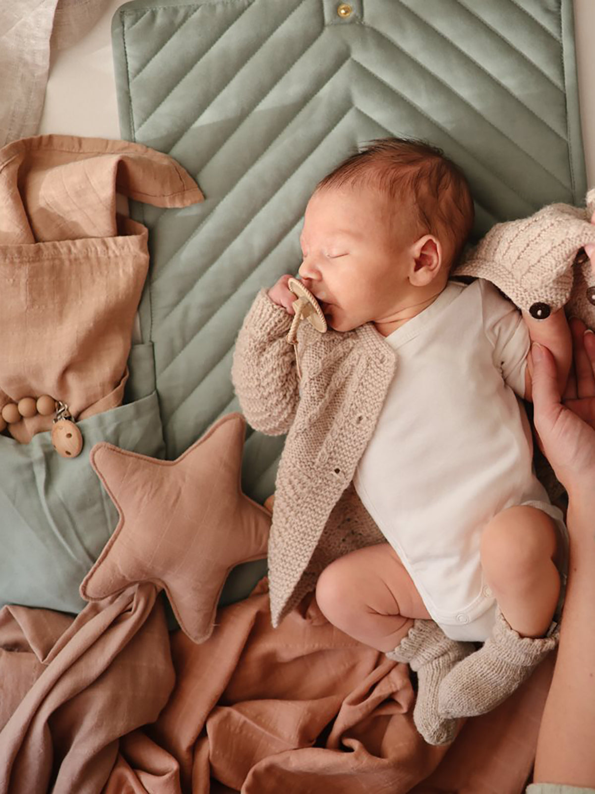 Mushie Roman Green portable change pad cover laid flat, soft fabric with a subtle green color and simple design for baby changing.