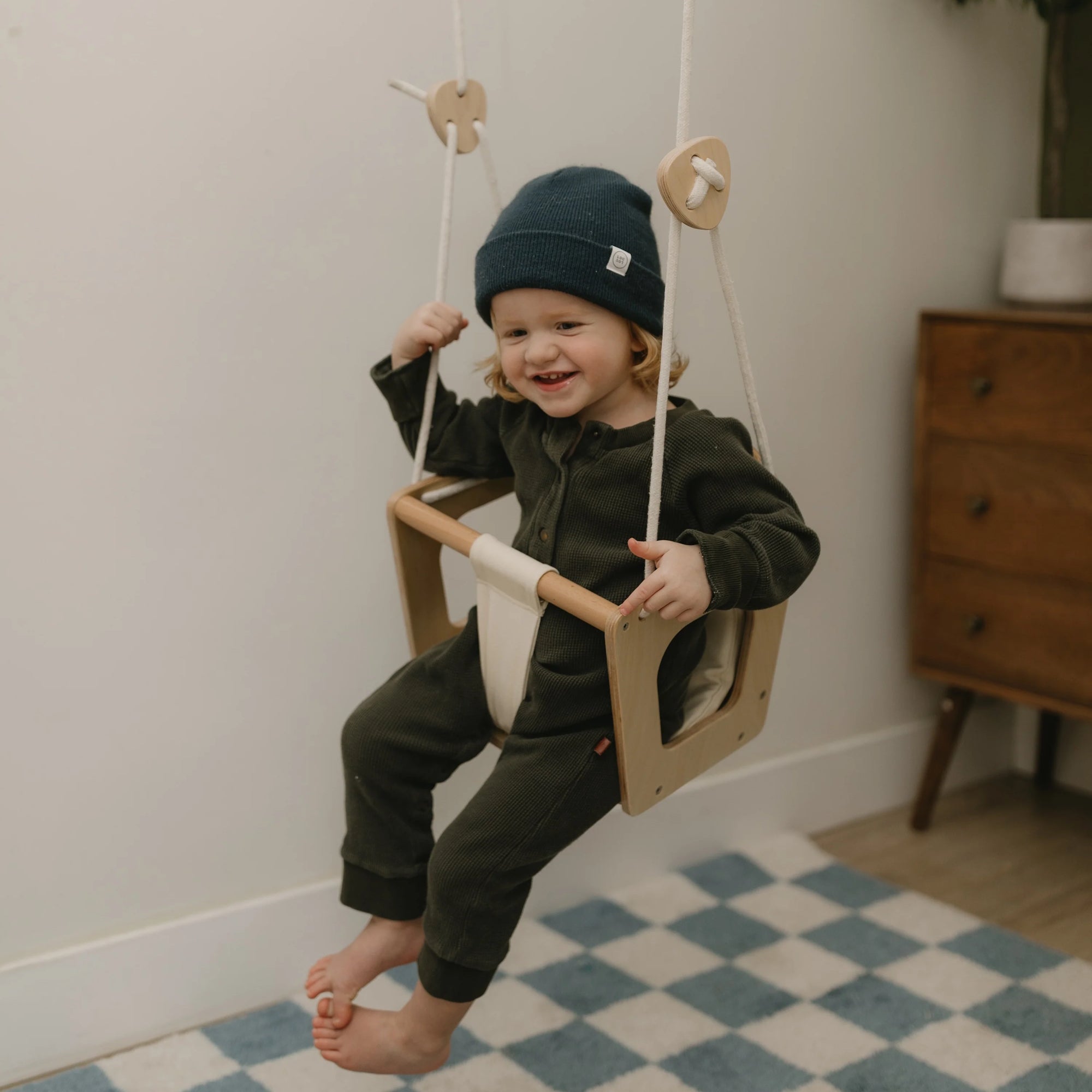 Kinderfeets Baby Swing hanging from a sturdy frame with soft fabric seat and safety straps for gentle rocking.