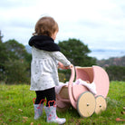 Wooden Kinderfeets Pram Walker in rose color, designed for toddlers, featuring a classic baby stroller shape and natural wood finish.