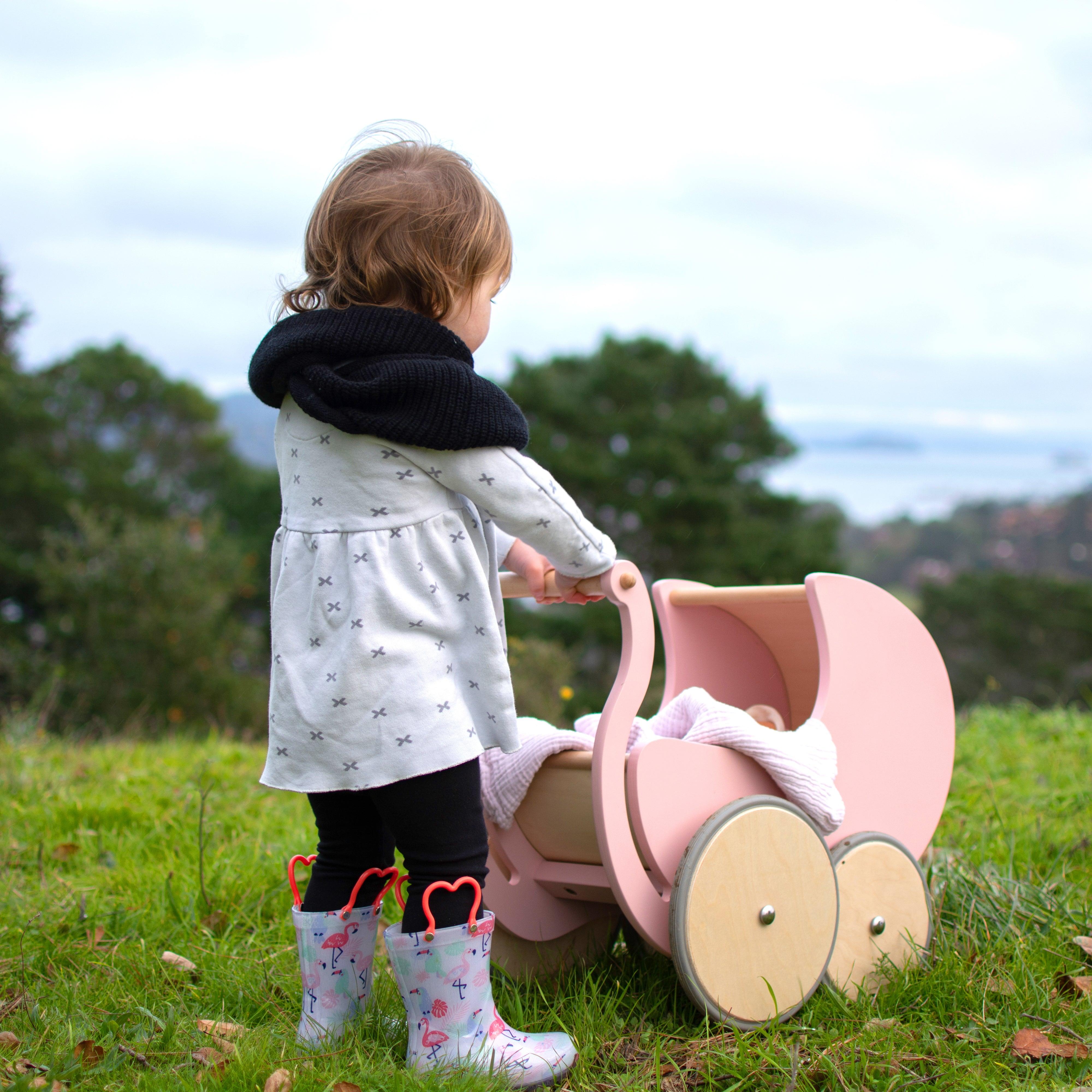 Wooden Kinderfeets Pram Walker in rose color, designed for toddlers, featuring a classic baby stroller shape and natural wood finish.