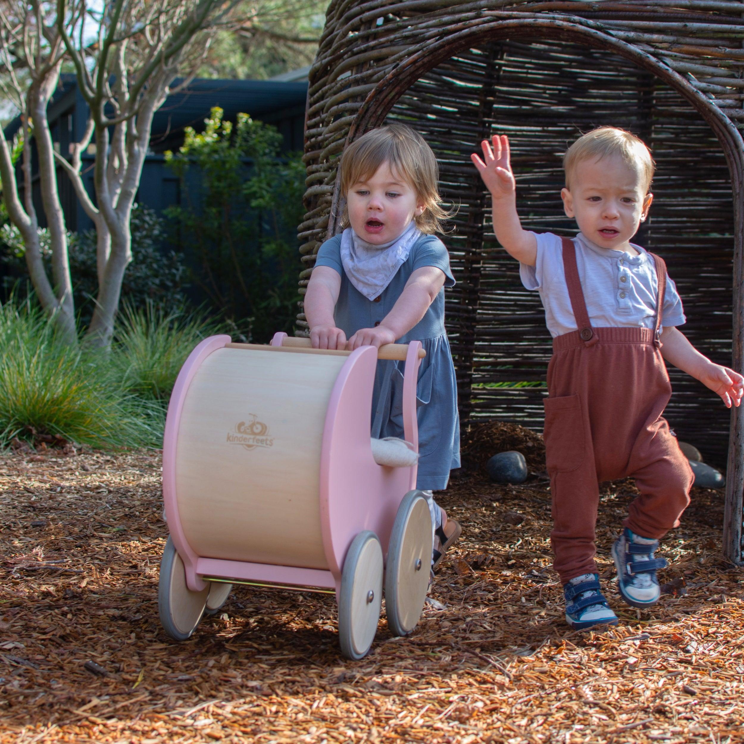 Wooden Kinderfeets Pram Walker in rose color, designed for young children, featuring a sturdy wooden frame and playful design.