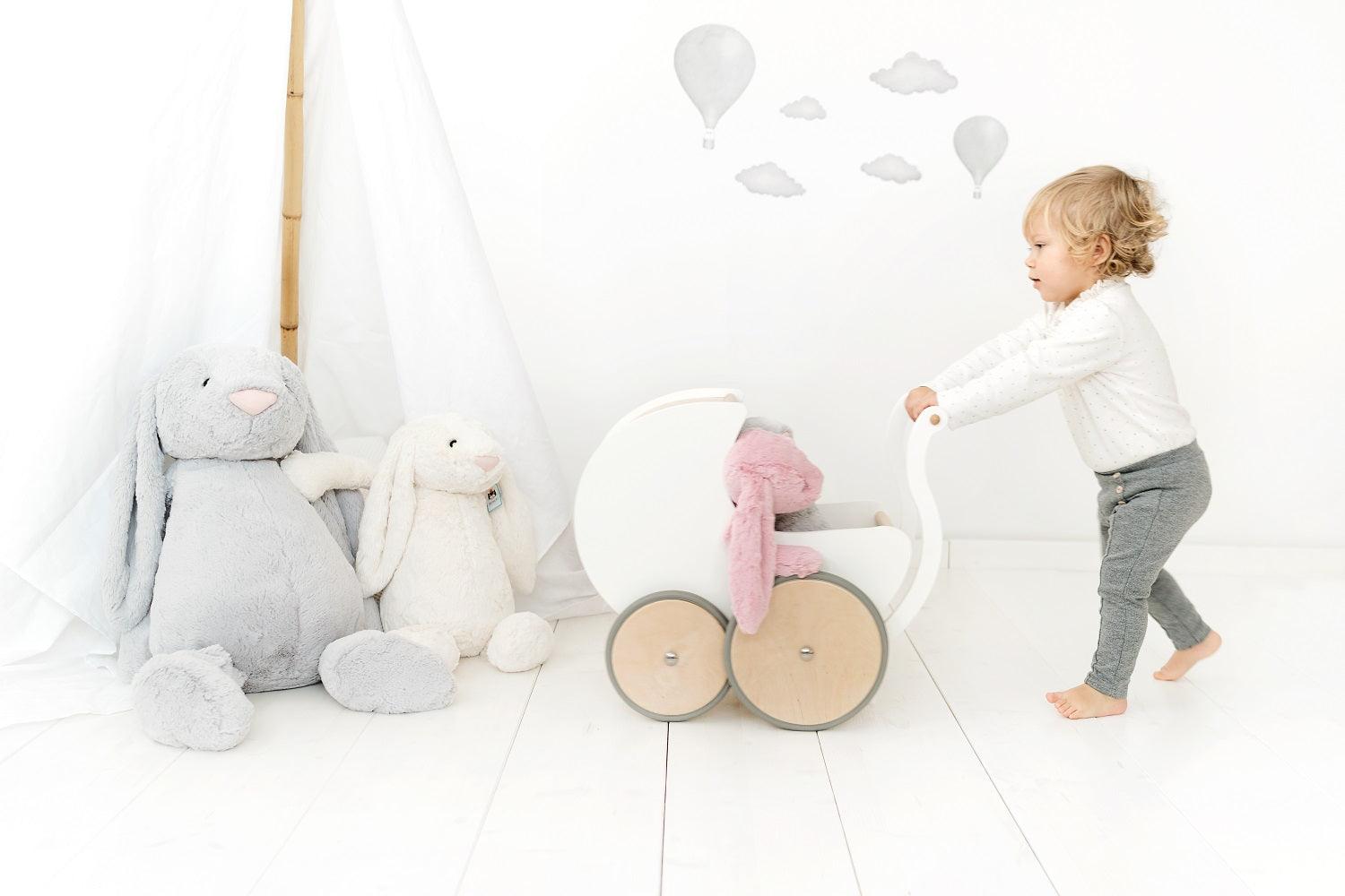 Wooden Kinderfeets Pram Walker in white, designed for toddlers, featuring a classic wooden frame and colorful toy accessories.