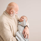 Love To Dream Swaddle Up™ Original 1.0 TOG grey swaddle with zip closure, soft fabric, and baby sleeping peacefully inside.