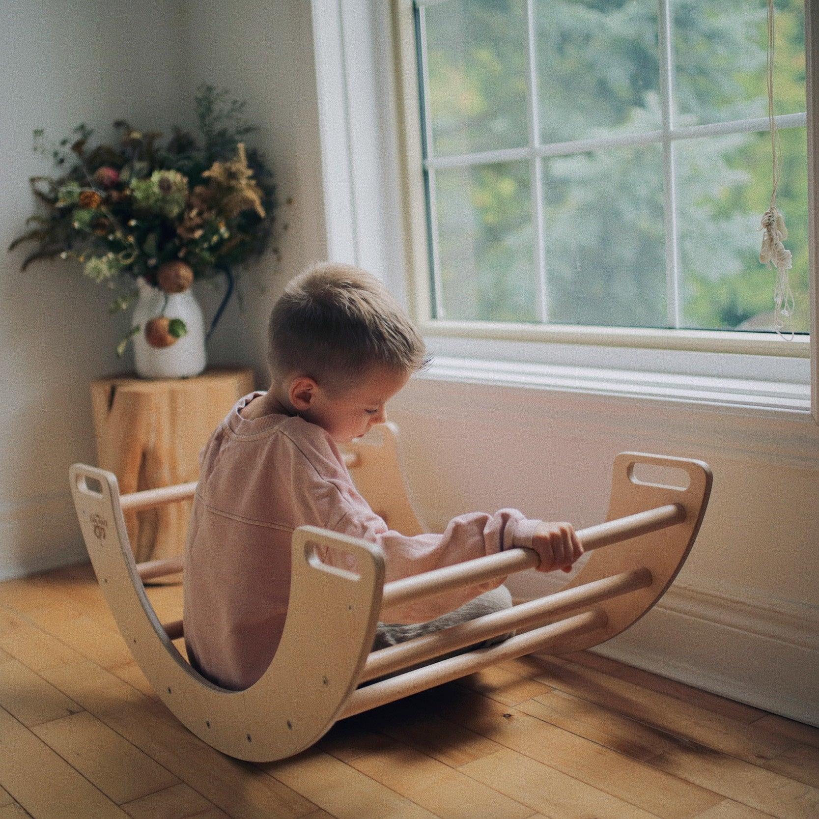 Kinderfeets Pikler climbing toy and rocking arch for children, featuring wooden construction and colorful climbing and rocking surfaces.