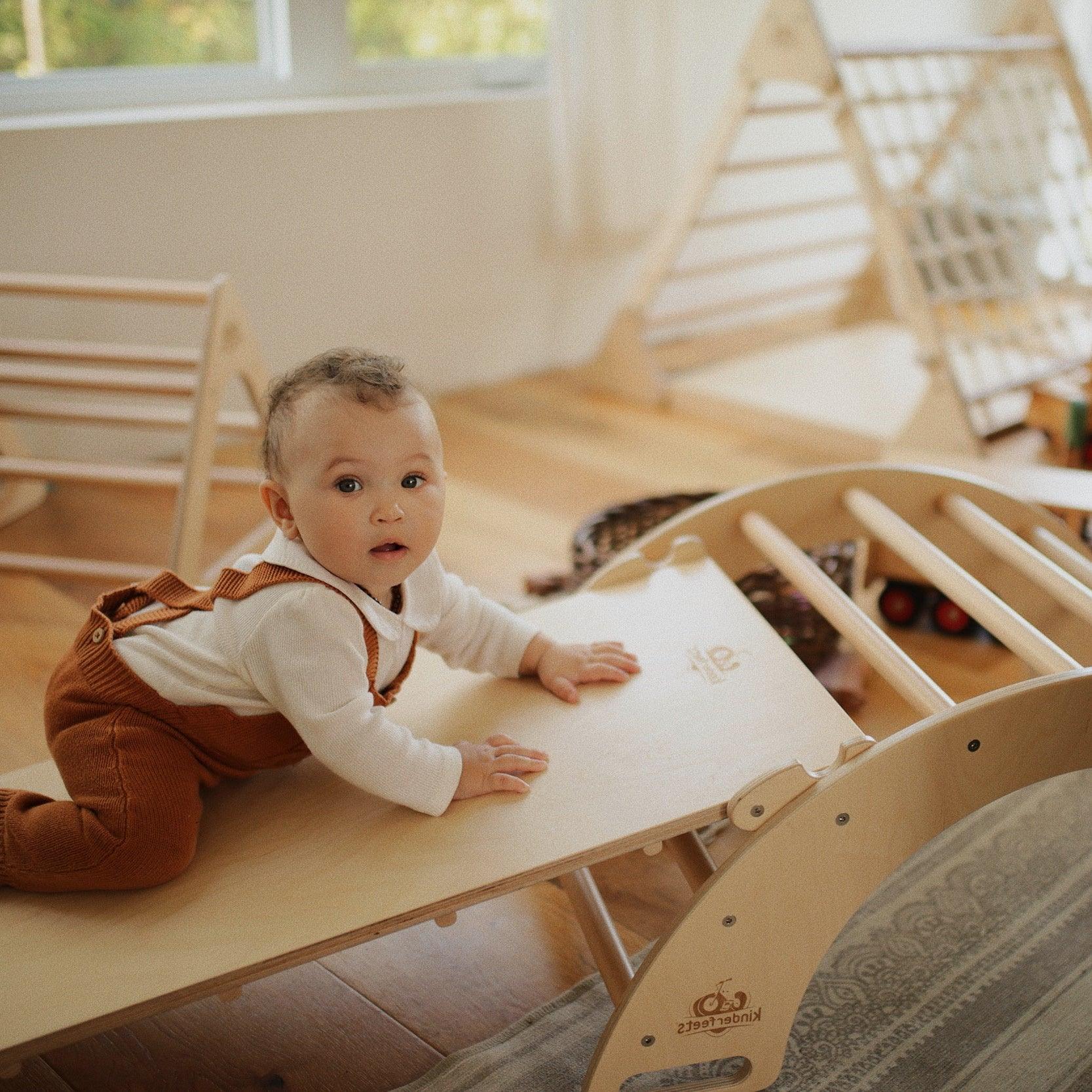 Kinderfeets Pikler ramp and slide climbing toy for children, with wooden structure and colorful slide in a playroom setting.