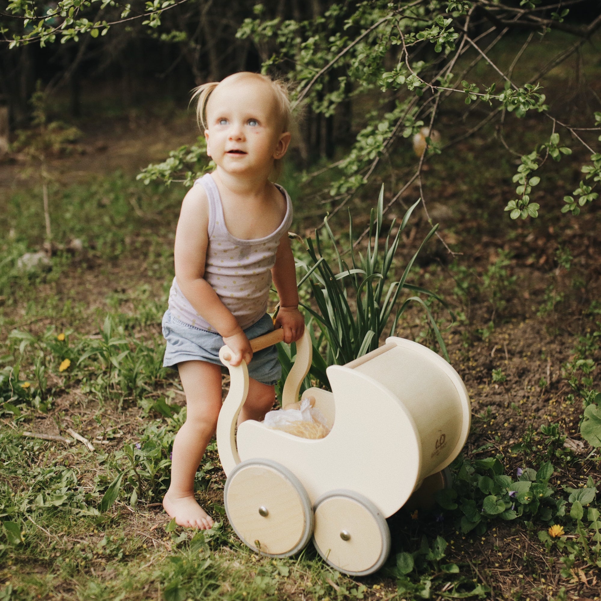 Wooden Kinderfeets Petit Pram toy with a natural wood finish, designed for children to simulate strolling and imaginative play.