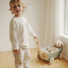 Child pulling a wooden Kinderfeets Pull Wagon toy with colorful wheels and sturdy handle, designed for young children’s outdoor play.