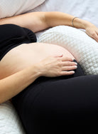 Belly Bliss pregnancy pillow in a neutral color, designed for comfort and support during pregnancy, shown in a cozy bedroom setting.