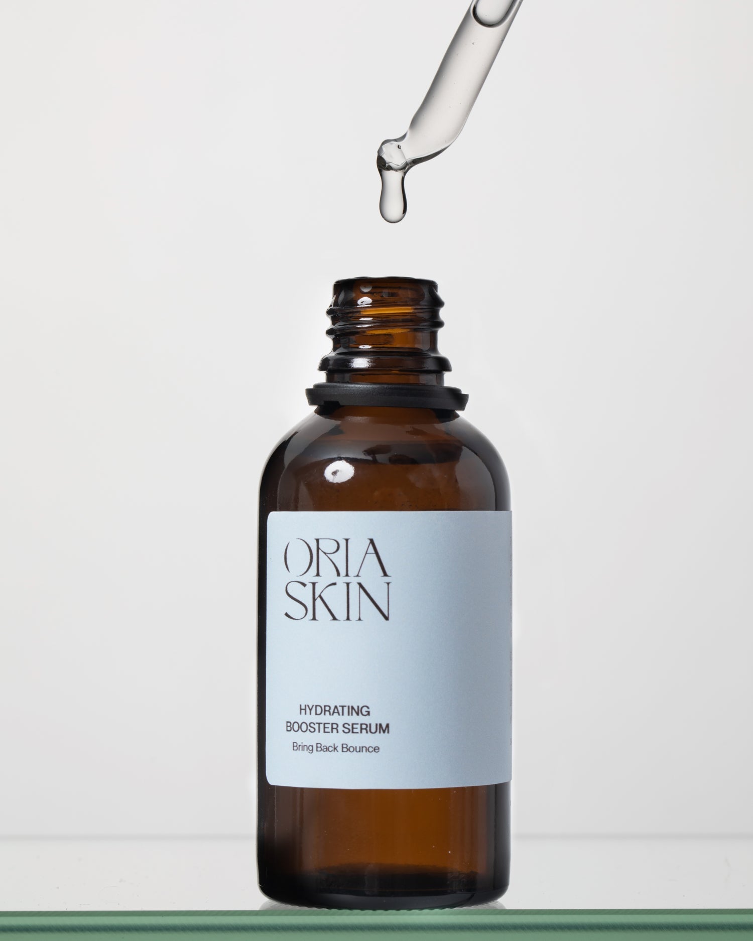 Oria Skin Hydrating Booster Serum in a clear glass bottle with a dropper, displaying the skincare product for hydration.