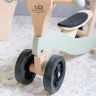 Kinderfeets Tiny Glider toy with wooden frame, colorful wheels, and handlebar, designed for young children to ride and play outdoors.