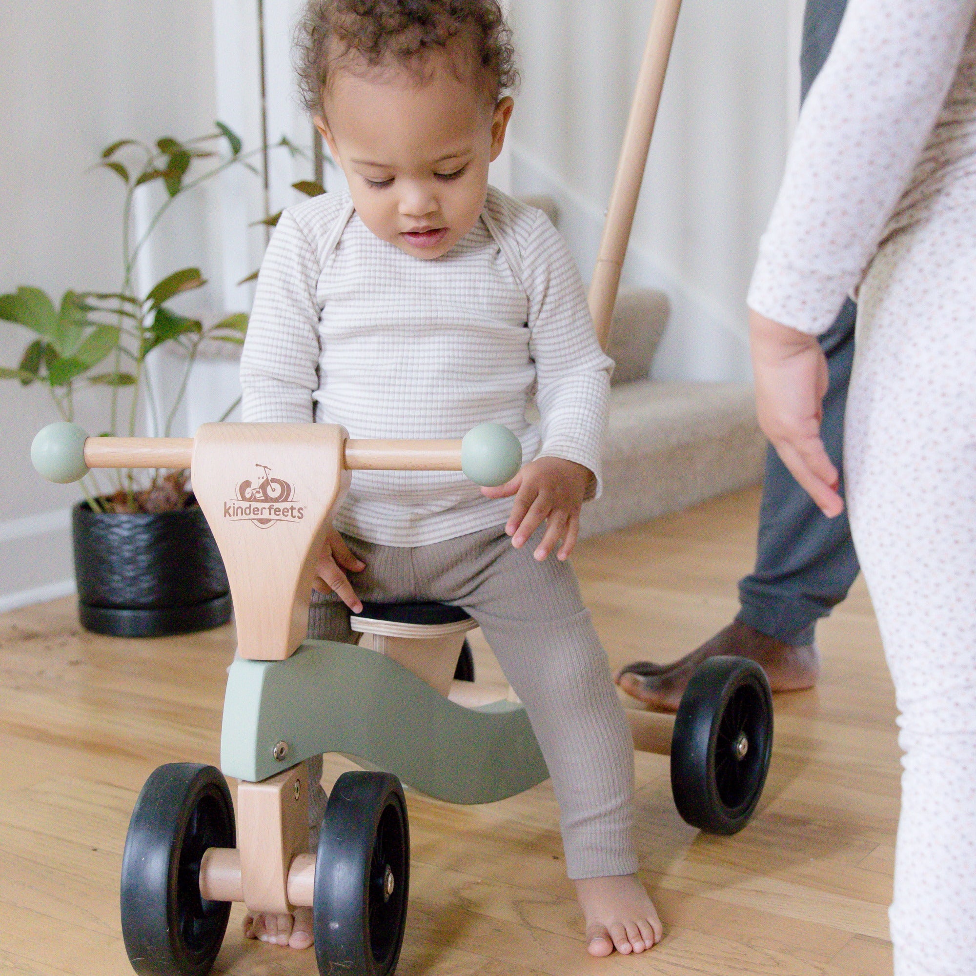 Kinderfeets Tiny Glider toy in vibrant colors, featuring a wooden frame and three wheels suitable for young children.