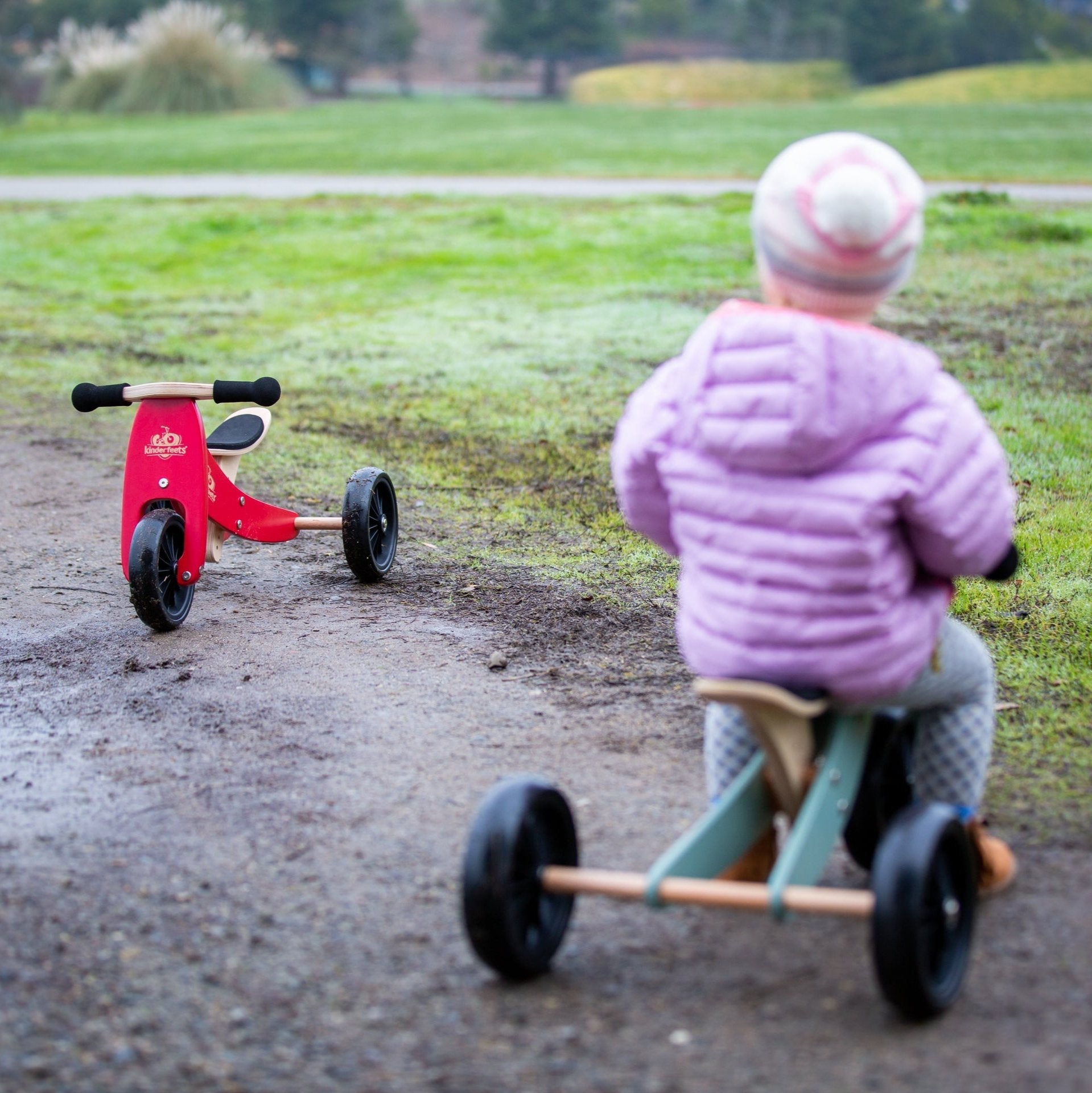 Kinderfeets Tiny Tot trike and balance bike in sage green with wooden handlebar and wheels, designed for young children learning balance.