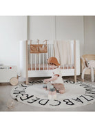 Mushie Crib Pocket with colorful rainbow design hanging on a crib side for easy storage and organization.
