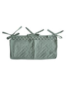 Mushie Roman Green crib pocket attached to a crib, made of soft fabric with a modern design for baby essentials storage.