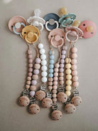 Mushie Cleo pacifier clip in mauve attached to a matching pacifier case, showcasing soft pastel color and durable design.