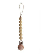 Mushie Cleo pacifier clip in muted yellow, attached to a matching pacifier case, showcasing a soft, minimalist design.