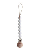Mushie Cleo Pacifier Clip in Halo White attached to a white pacifier case, featuring a soft fabric strap and clip for easy attachment.